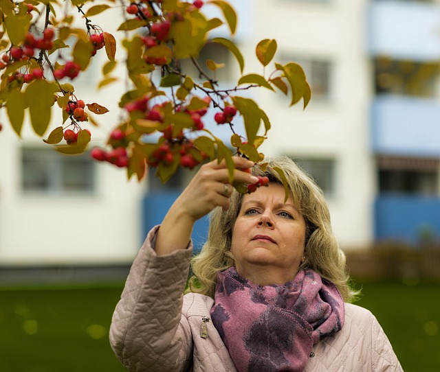 Neues in der Mitte des Lebens entdecken: Frau fasst Zweig mit roten Beeren an.